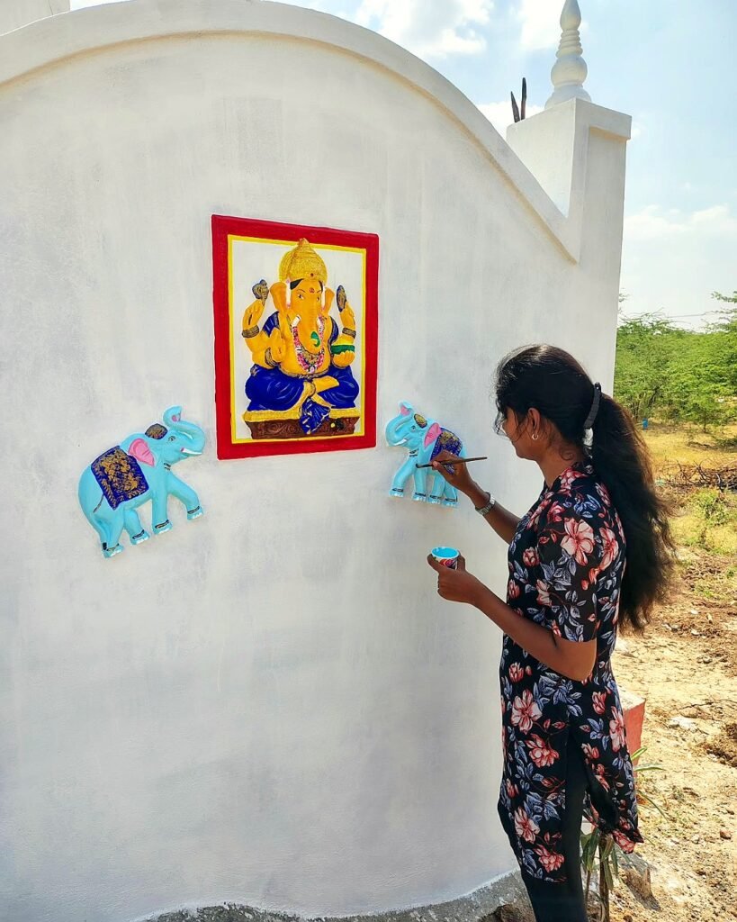 Bhuvi hand-painting a Vinayagar wall mural at a home in Tamil Nadu